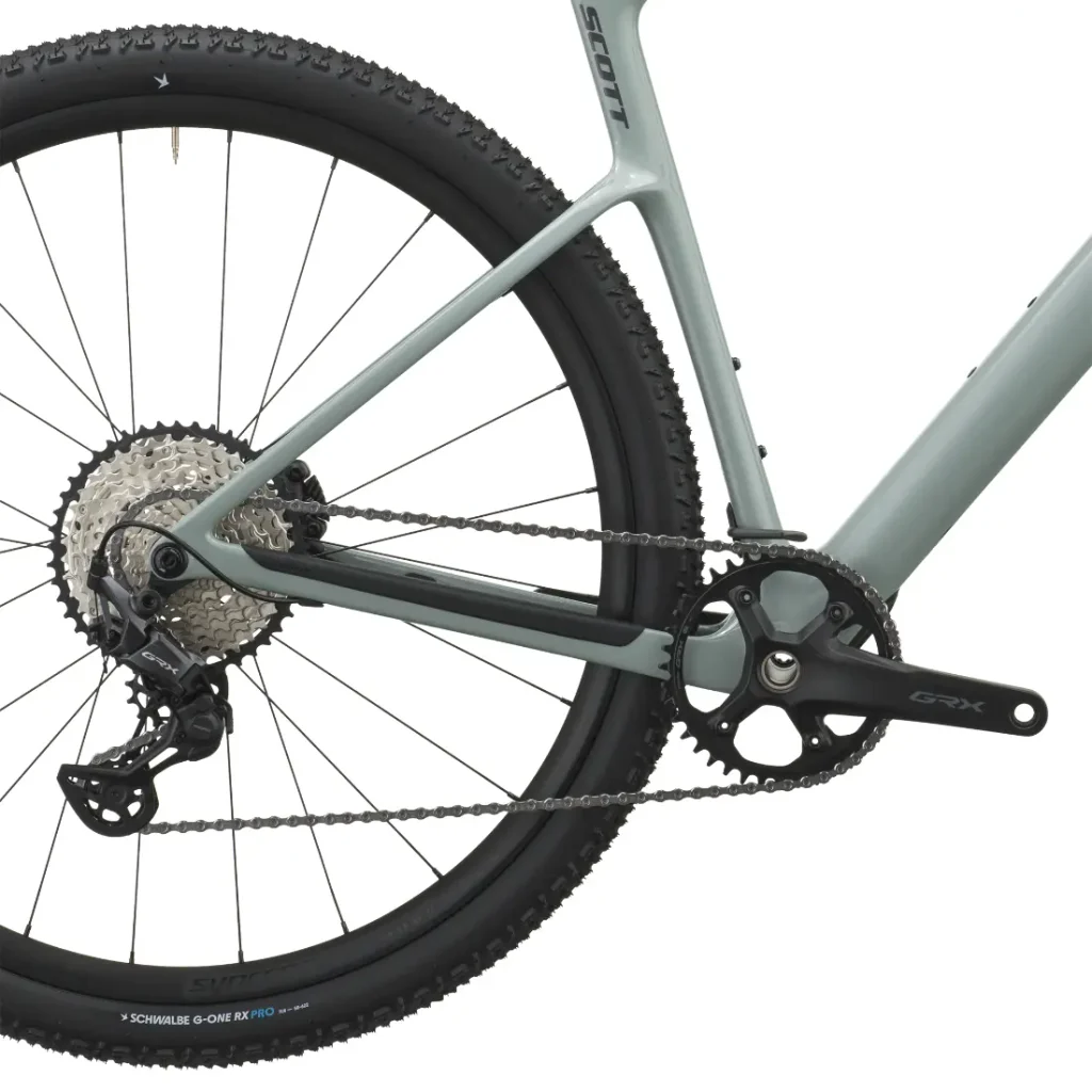 Primer plano de la rueda trasera, el desviador, la cadena, el cassette y el juego de bielas de una SCOTT Addict Gravel 2027 con cuadro gris claro mate. Esta bicicleta gravel polivalente cuenta con componentes de primera categoría diseñados para ofrecer rendimiento y versatilidad.