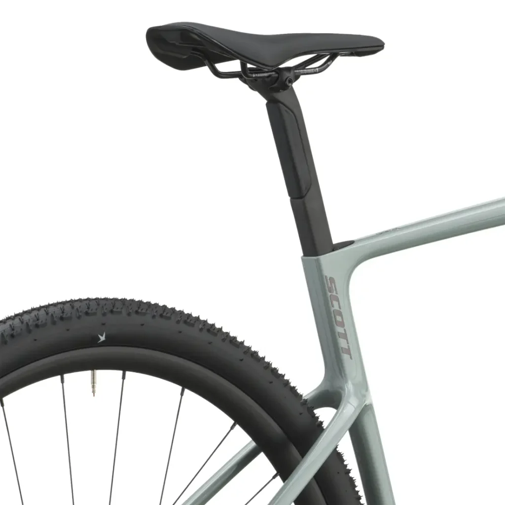 Primer plano del cuadro gris claro de una bicicleta de gravel, en el que se aprecian el sillín, la tija del sillín y la rueda trasera con la banda de rodadura visible. La marca «Scott» aparece impresa en el cuadro, lo que destaca la cómoda y versátil SCOTT Addict Gravel 2027.