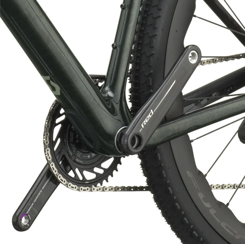 Primer plano de un juego de bielas, un plato y una rueda trasera con neumático texturizado, con especial atención a los brazos de los pedales y la unión con el cuadro de la bicicleta de gravel polivalente SCOTT Addict Gravel 2027.