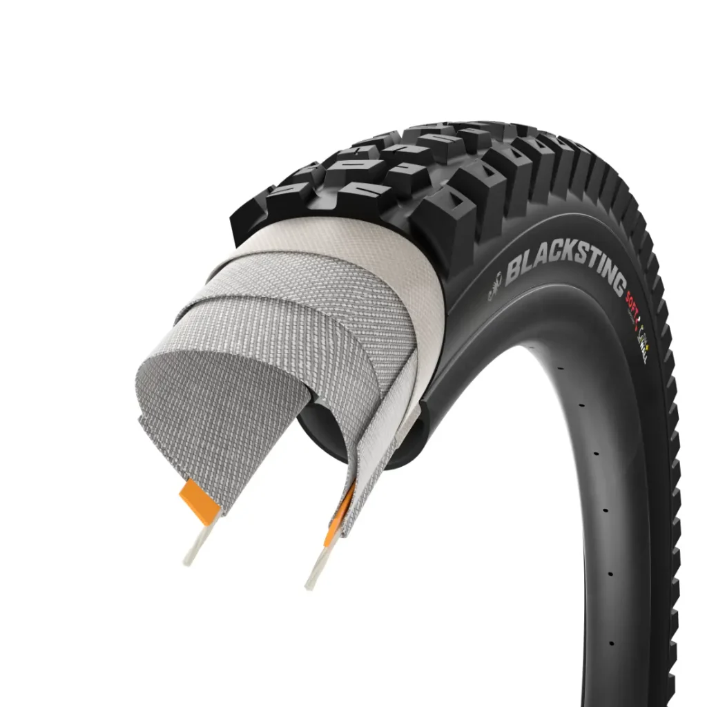 La sección transversal de una cubierta de bicicleta BLACKSTING, inspirada en los neumáticos Scorpion MTB de Pirelli, muestra múltiples capas protectoras y cordones internos debajo de la banda de rodadura exterior.