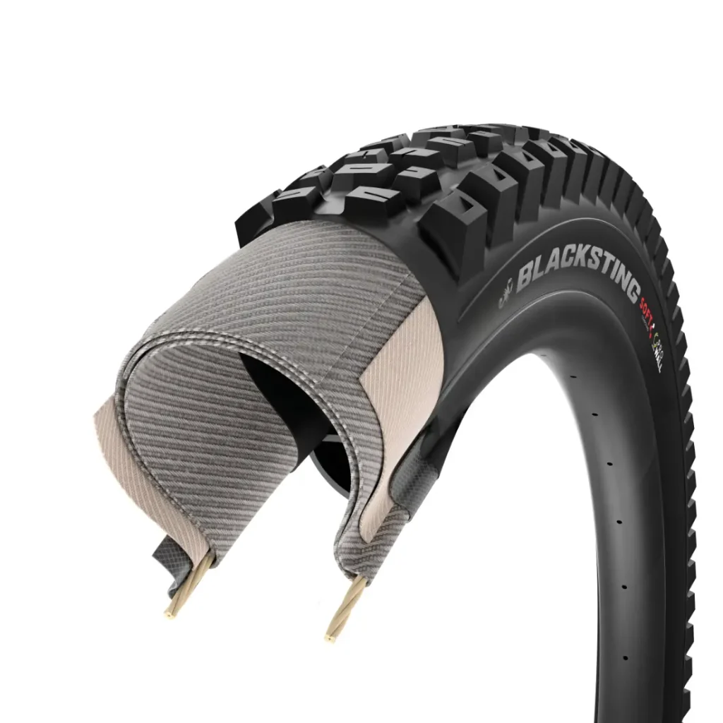 Una sección transversal de una cubierta de bicicleta Blacksting en la que se aprecian la banda de rodadura, las capas internas y las cámaras, lo que pone de relieve su estructura multicapa y su diseño resistente a los pinchazos, similar al de las cubiertas de MTB de gama alta como la Pirelli Scorpion, diseñadas para ofrecer un agarre y una durabilidad superiores en las exigentes condiciones de las disciplinas de gravedad en MTB.