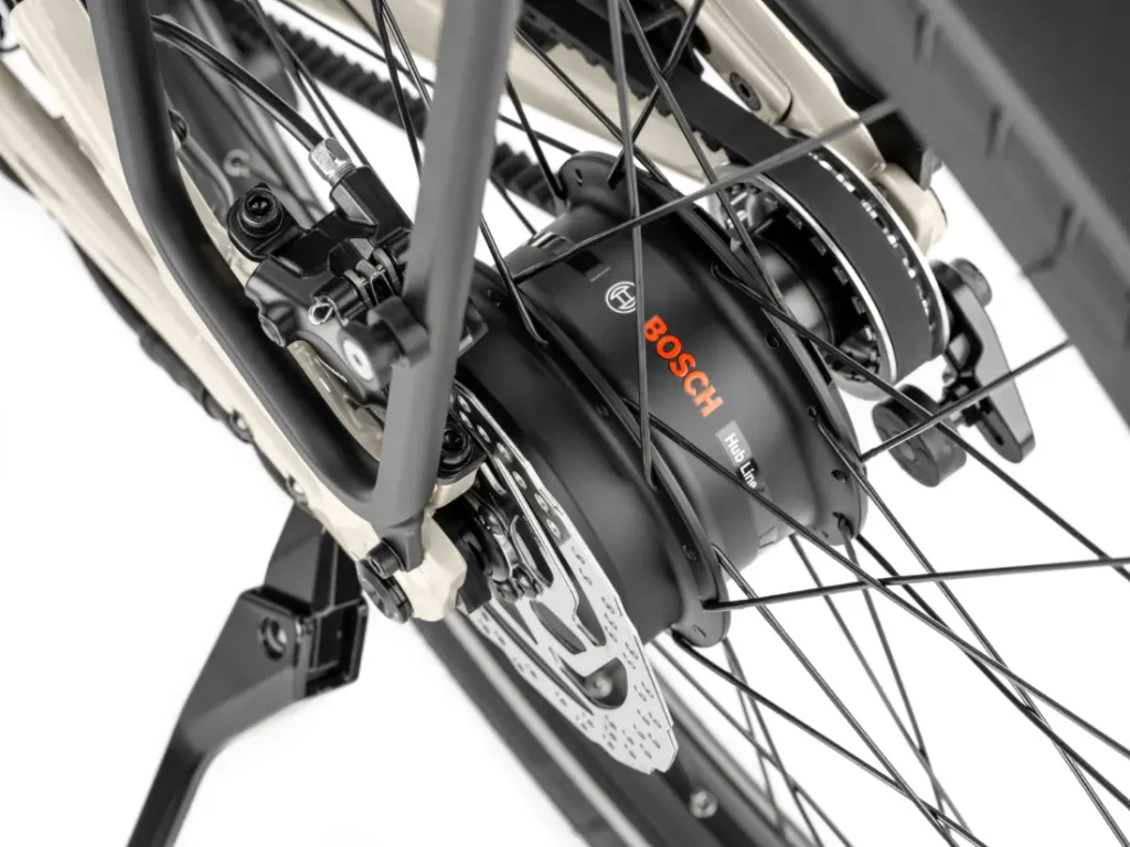 Primer plano de la rueda trasera de la bicicleta Moustache Lundi 27, equipada con un motor eléctrico Bosch integrado en el buje, un sistema de frenos de disco y radios: perfecta para desplazarse sin esfuerzo por la ciudad.