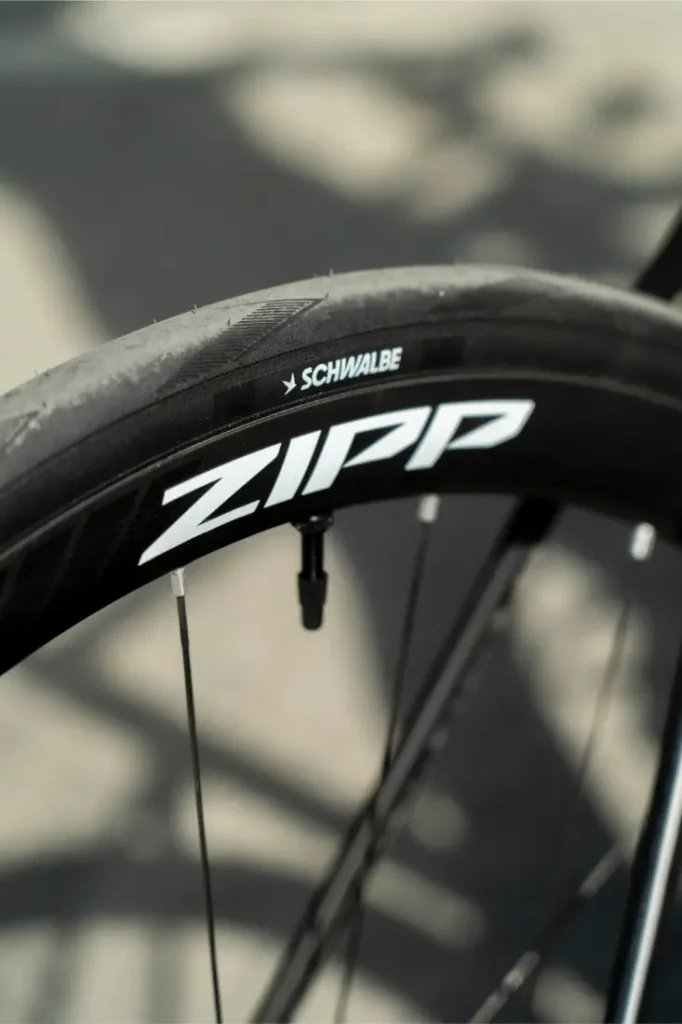 Primer plano de una rueda de bicicleta en el que se aprecia el logotipo «ZIPP» en la llanta y la marca «Schwalbe» en el neumático; destaca el neumático de alto rendimiento Schwalbe Pro One Aero montado en la rueda trasera.