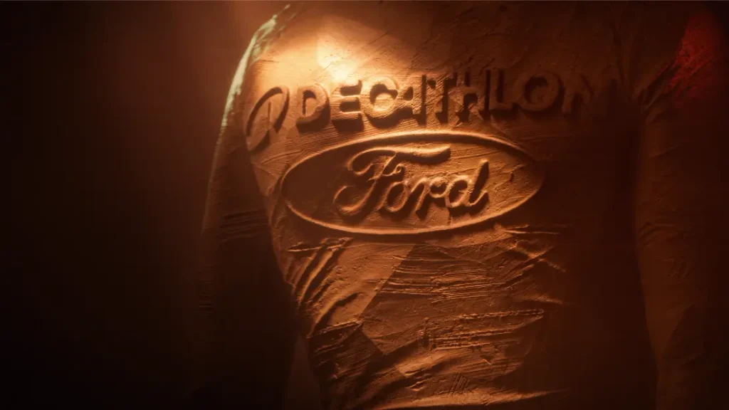 Logotipos de Decathlon y Ford grabados en relieve sobre una superficie texturizada de color arcilla.