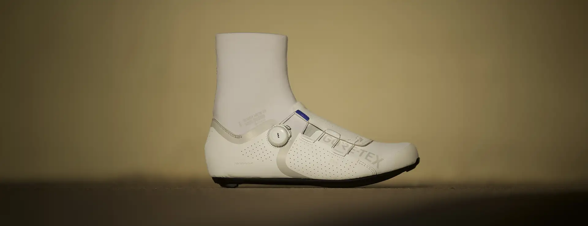 Una zapatilla de ciclismo Northwave Celsius R Arctic GTX de color blanco, con una polaina alta integrada en el tobillo y un sistema de cierre con rueda giratoria.