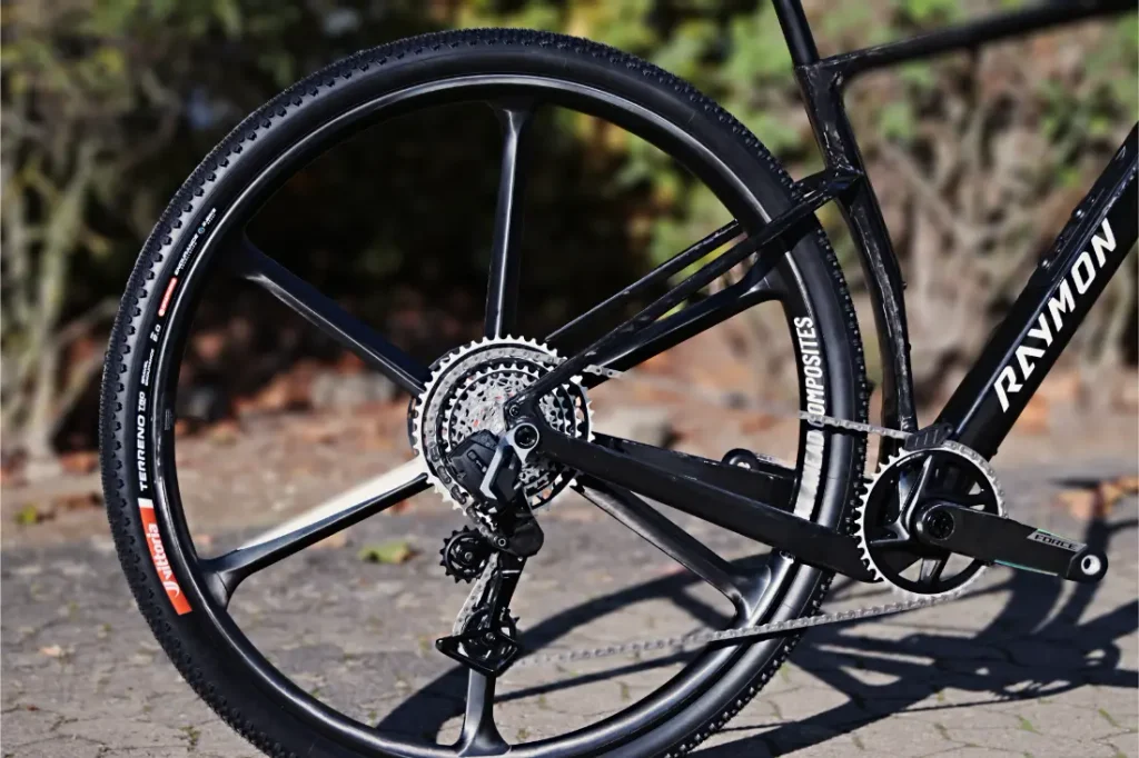 Vista trasera de una bicicleta de gravel RAYMON equipada con una rueda de carbono con radios, un desviador y una transmisión.