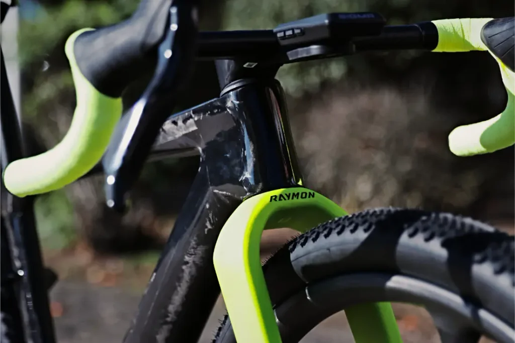 Primer plano de un cuadro de bicicleta de gravel RAYMON con cinta de manillar en amarillo neón y una horquilla delantera a juego.