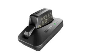 Un cargador de batería de bicicleta electrónico SRAM negro, parte de las Novedades SRAM febrero 2026, con una batería insertada y tres luces indicadoras LED en el lateral.