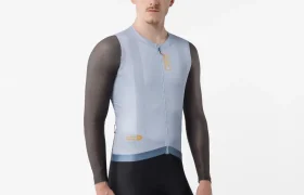 Una persona que lleva un maillot de ciclismo Corretto LS de color azul claro, de manga larga, y unos pantalones cortos negros, de pie sobre un fondo blanco liso.