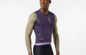 Hombre que lleva un maillot de ciclismo morado sin mangas, que recuerda al modelo «Transition» de Castelli, combinado con mangas largas de color beige y pantalones cortos negros, de pie sobre un fondo blanco liso.