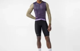 Un hombre posa sobre un fondo blanco con un elegante maillot de ciclismo sin mangas Castelli Transition, que complementa con calcetines blancos y zapatillas de ciclismo; tiene la mano izquierda en la cadera y el brazo derecho relajado a lo largo del cuerpo.