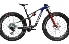 Bicicleta de montaña Van Rysel con suspensión total, con cuadro azul y negro, horquilla delantera roja y ruedas de carbono negras.