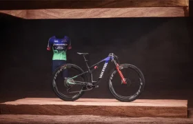 Una bicicleta de montaña Van Rysel expuesta junto a un maillot de ciclismo Decathlon-Ford a juego sobre una plataforma elevada.