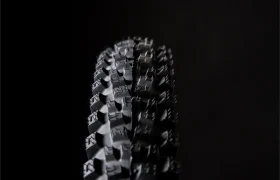 Primer plano de un neumático negro Pirelli Scorpion para bicicleta de montaña con dibujo de tacos, fotografiado sobre un fondo oscuro. Perfectos para afrontar senderos que desafían la gravedad, estos neumáticos de MTB están diseñados para ofrecer el máximo agarre y control.