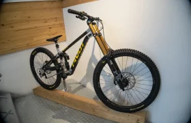 Una elegante bicicleta de montaña negra y amarilla de Central Europea de Pivot se encuentra orgullosamente montada en un soporte de madera contra la pared.