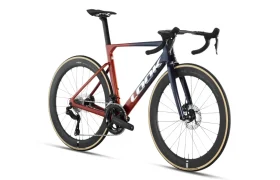 Una bicicleta de carretera con ruedas de perfil alto, manillar de carretera y un cuadro con un degradado de rojo a azul en el que se lee «LOOK» en el tubo diagonal: se trata de la LOOK 795 Blade RS 3, fabricada en Nevers y diseñada para la velocidad.