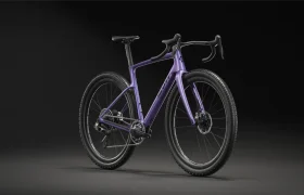Se muestra una bicicleta polivalente SCOTT Addict Gravel 2027 en color morado, con manillar curvo y frenos de disco, sobre un fondo negro, ligeramente girada hacia la derecha. Perfecta para paseos cómodos por cualquier terreno.