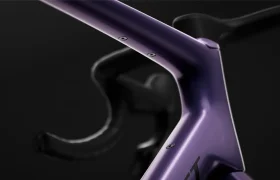 Primer plano del manillar y la potencia de una bicicleta SCOTT Addict Gravel 2027 de color morado mate sobre un fondo oscuro, en el que destacan sus líneas suaves y el diseño integrado y polivalente de esta bicicleta de gravel.