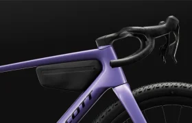 Primer plano de una bicicleta SCOTT Addict Gravel 2027 de color morado, con especial atención al manillar, el cuadro y una bolsa negra para accesorios fijada en el triángulo del cuadro, todo ello sobre un fondo negro, que refleja el espíritu polivalente de esta bicicleta gravel.