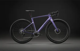 Una bicicleta de gravel de color morado, con manillar de carretera y frenos de disco, se ve sobre un fondo oscuro, vista de perfil, lo que refleja la versatilidad de una bicicleta polivalente como la SCOTT Addict Gravel 2027.