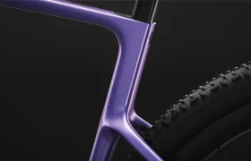 Primer plano del cuadro y la rueda trasera de una bicicleta SCOTT Addict Gravel 2027 de color morado sobre un fondo negro, en el que se destacan los contornos suaves, la geometría cómoda y el moderno diseño gravel de la bicicleta.
