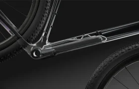 Primer plano del cuadro polivalente de la bicicleta SCOTT Addict Gravel 2027, con una sección transparente que muestra el paso interno de los cables y dos ruedas parcialmente visibles sobre un fondo oscuro. El diseño destaca lo cómoda y elegante que resulta la bicicleta, perfecta para salidas versátiles.