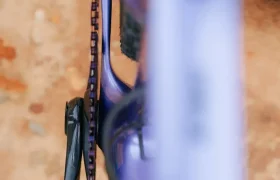 Primer plano de un cuadro de bicicleta SCOTT Addict Gravel 2027 de color morado, en el que se aprecian el plato, el pedal y la rueda trasera, fotografiado desde arriba sobre una superficie de tierra, lo que destaca su diseño polivalente para gravel.