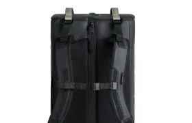 Una mochila Db negra mostrada desde atrás, con correas acolchadas para los hombros, una correa para el pecho y una cremallera central, perfecta para cualquier sistema de viaje.