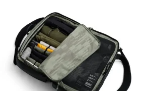 Una bolsa de viaje que se abre y muestra compartimentos organizados con ropa y objetos bien empaquetados en su interior: el sistema de viaje perfecto para ciclistas, inspirado en la colaboración ASSOS x Db.