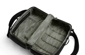 Mochila de viaje negra abierta de ASSOS sobre fondo blanco, que muestra sus compartimentos interiores vacíos y sus correas organizadoras, perfecta para el sistema de viaje de los ciclistas que buscan un almacenamiento eficiente.
