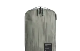 Cubo de embalaje rectangular verde oliva de Db con sutiles dibujos verticales, cierre de cremallera en la parte superior y una pequeña etiqueta negra con texto blanco en la esquina inferior derecha: un complemento ideal para cualquier sistema de viaje.
