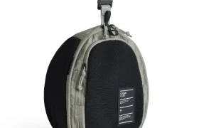 Bolsa redonda bicolor gris y negra con cremallera, clip superior y etiqueta frontal, parte del sistema de viaje ASSOS x Db, diseñada para ciclistas y de pie sobre fondo blanco.