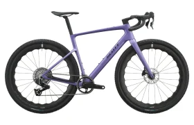Se muestra de perfil, sobre un fondo blanco, una bicicleta SCOTT Addict Gravel 2027 de color morado, con manillar de carretera, frenos de disco, neumáticos anchos y un elegante cuadro de carbono. Esta bicicleta de gravel polivalente combina un diseño moderno con un rendimiento versátil para todas tus aventuras.