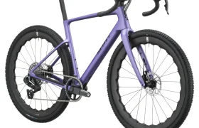 En un fondo blanco se muestra una bicicleta SCOTT Addict Gravel de color morado, con manillar de carretera, frenos de disco y neumáticos con tacos.