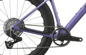 Primer plano de la rueda trasera, la cadena, el cassette, el desviador y la biela de una SCOTT Addict Gravel 2027 de color morado, en el que se aprecia parte del cuadro de la bicicleta y la banda de rodadura del neumático. El diseño versátil de esta bicicleta de gravel destaca sus prestaciones como bicicleta polivalente para diversos terrenos.