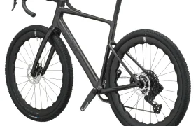En un fondo blanco se muestra una bicicleta SCOTT Addict Gravel 2027 de color negro, con manillar de carretera, neumáticos de banda de rodadura gruesa, frenos de disco y cuadro de fibra de carbono. Este modelo polivalente ofrece una conducción cómoda en diversos terrenos.