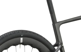 Primer plano de la rueda trasera, la tija del sillín y el sillín de una bicicleta negra SCOTT Addict Gravel 2027, en el que se aprecia la banda de rodadura del neumático y parte del cómodo y polivalente cuadro de la bicicleta, en una vista lateral sobre un fondo blanco.