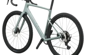 Bicicleta SCOTT Addict Gravel 2027 de color gris claro, con manillar de carretera, frenos de disco y neumáticos con tacos, vista desde un ángulo de tres cuartos trasero sobre un fondo blanco. Esta bicicleta de gravel, polivalente y cómoda, está diseñada para ofrecer versatilidad y comodidad en una gran variedad de terrenos.