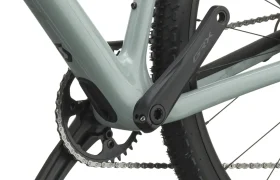 Primer plano de un juego de bielas, un plato y una rueda trasera de bicicleta, en el que destaca la biela GRX montada en un cuadro de bicicleta SCOTT Addict Gravel 2027 de color gris claro, con la banda de rodadura de los neumáticos de tacos bien visible. Esta bicicleta polivalente y cómoda está diseñada para ofrecer versatilidad y comodidad en cada salida.