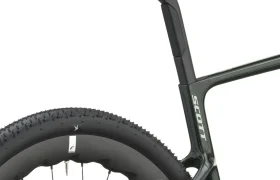 Primer plano de la rueda trasera, el tubo del sillín y el sillín de una bicicleta de gravel, en el que se aprecia una cubierta gruesa y parte del cuadro de la bicicleta con la inscripción «SCOTT Addict Gravel 2027». Este diseño polivalente destaca tanto por su resistencia como por su versatilidad para diferentes tipos de terreno.
