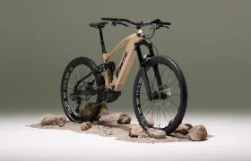 Una Fantic e-MTB beige con suspensión total, propulsada por un motor Bosch CX Gen5, se muestra en una superficie rocosa sobre un fondo verde apagado.