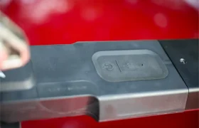 Primer plano de una cerradura electrónica con un botón de encendido y una llave cerca, con un fondo rojo difuminado, similar al diseño seguro e innovador del portabicicletas Allen Smart Suction.
