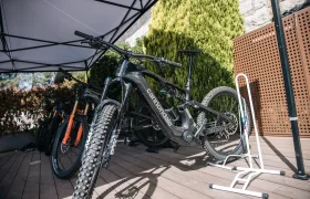 Una bicicleta de montaña Cannondale negra está aparcada en una cubierta de madera bajo un toldo, junto a otras bicicletas y un soporte blanco, lista para una actualización Bosch Performance que promete más potencia y una mejor experiencia sobre la bici.