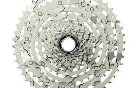Un casete de bicicleta plateado Edición Aluminio Pulido con múltiples piñones dispuestos en un patrón circular, visto desde arriba, perfecto para mejorar su Shimano CUES u otras configuraciones de grupos de carretera.