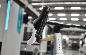 Primer plano de un manillar de bicicleta y una palanca de freno en un taller con fondo borroso.