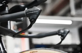 Primer plano de la palanca de cambios y el manillar de una bicicleta Campagnolo, con un fondo borroso.