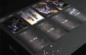 Varias cartas coleccionables, entre las que se incluyen las de la «Anniversary Edition» y las de la «edición limitada TRP EVO PRO», con imágenes de personajes y autógrafos en color dorado, se exhiben sobre una superficie oscura.