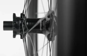 Primer plano del buje de una rueda de bicicleta con los radios que se extienden hacia fuera, fotografiado en blanco y negro sobre un fondo claro.