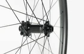 Primer plano de una rueda de bicicleta en el que se aprecian los radios negros y un buje central con la inscripción «300», sobre un fondo blanco liso.