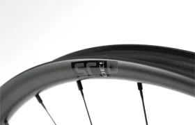 Primer plano de una llanta de bicicleta negra con radios y una etiqueta en la que se lee «SC 30» sobre un fondo blanco.